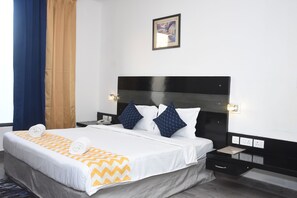 Een hotelkamer met een bed, een nachtkastje, een wandlamp en een schilderij.