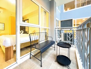 A modern hotel room with a bed, a bench, and a small table with a tray. - Bayshore Luxe by Prime (Parañaque)