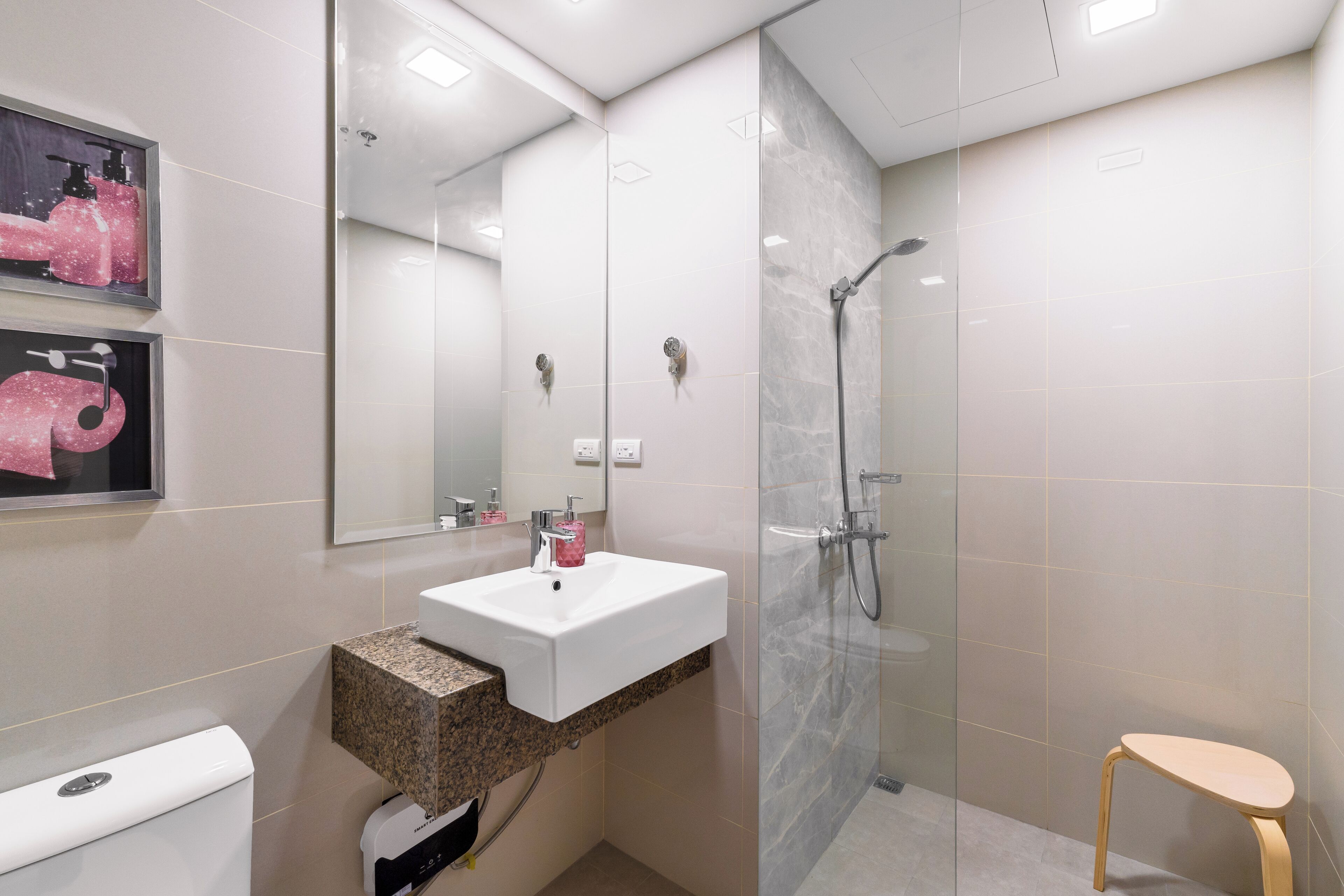 A modern bathroom with a white sink, marble countertop, and a glass shower enclosure.