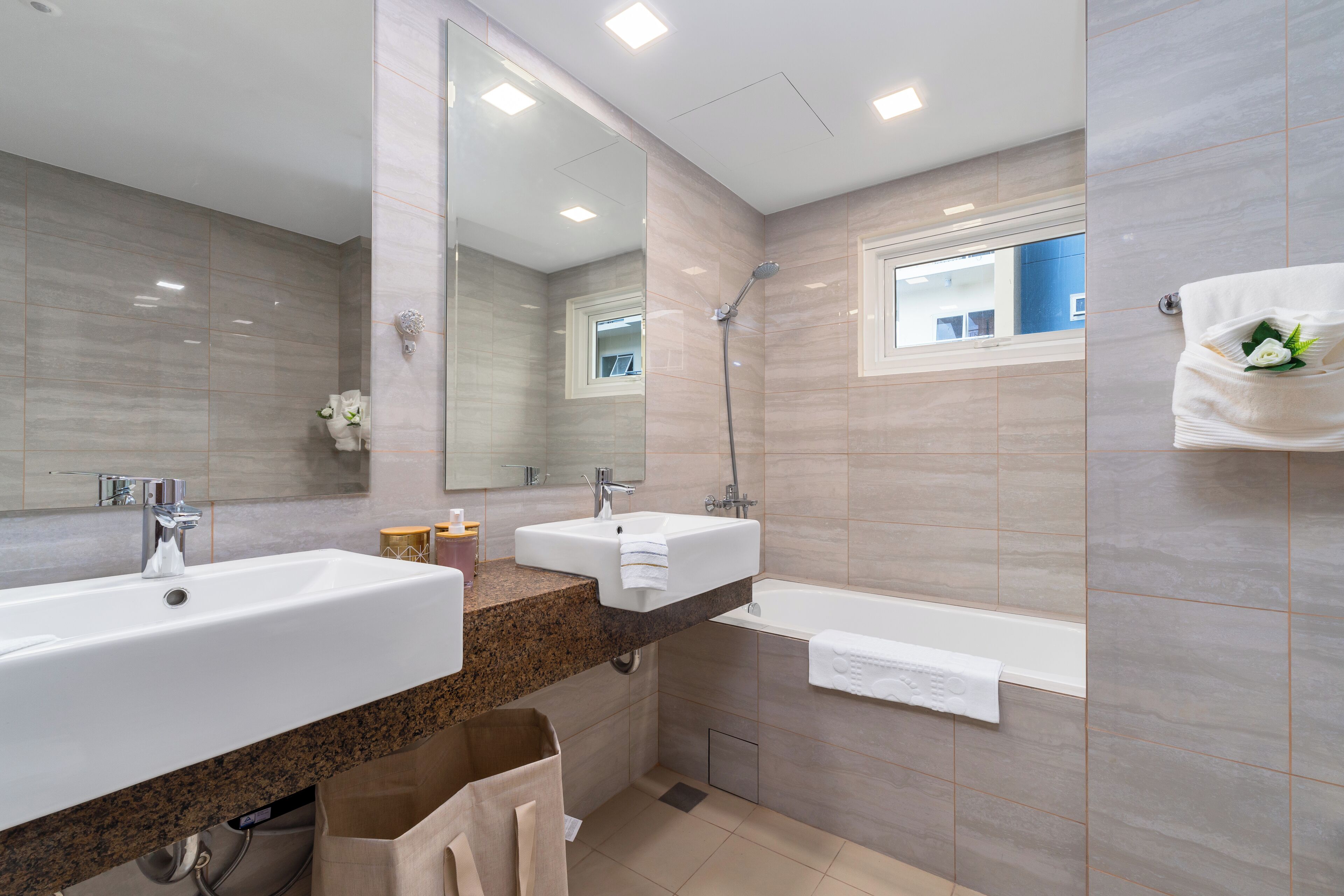 A modern bathroom with two sinks, a bathtub, and a shower.