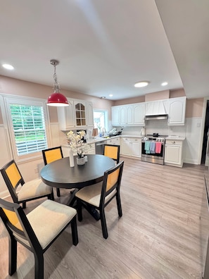 A modern kitchen with white cabinets, a round dining table, and chairs. - The peace and quiet of home, with everything nearby (Matthews)
