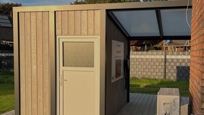 Un petit abri en bois, utilisé comme remise, avec une porte et une affiche accrochée au mur.