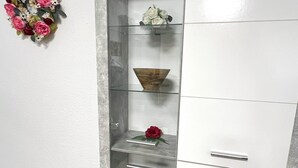Un meuble moderne doté de plusieurs étagères et de tiroirs, agrémenté d’objets décoratifs tels que des fleurs et un bol.