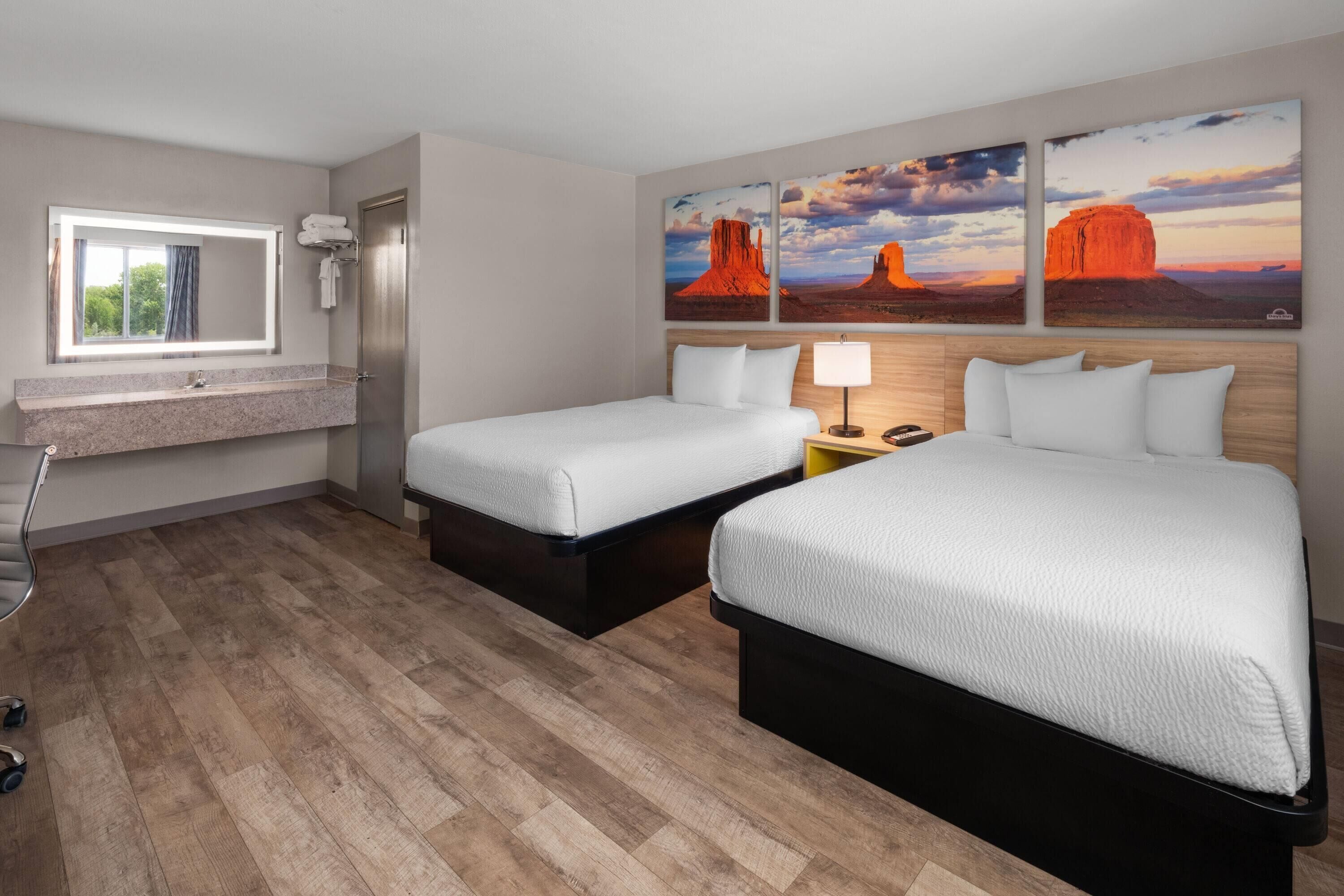 Una habitación de hotel con dos camas, un baño con espejo y una ventana.