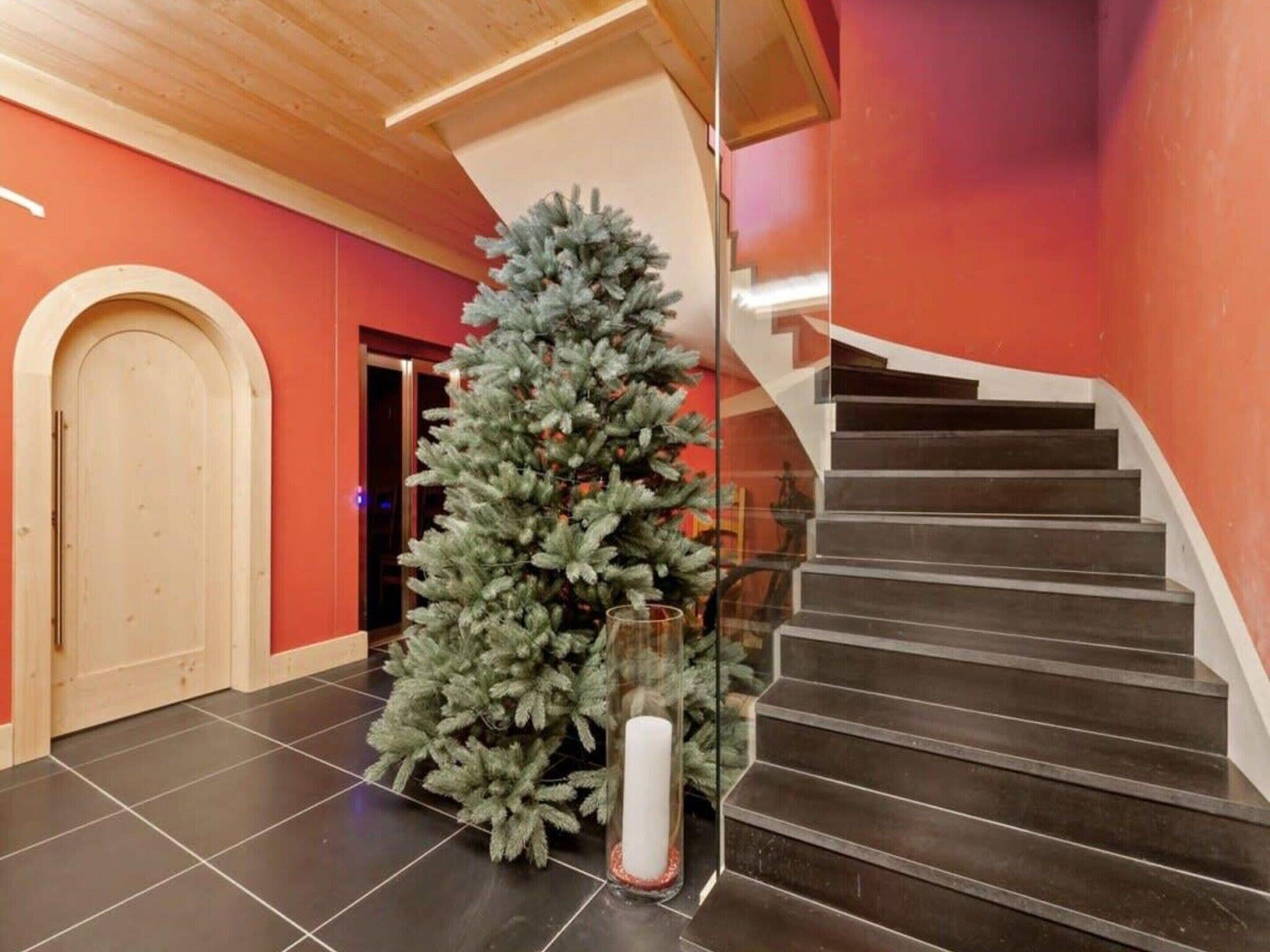 Una scala con ringhiera in vetro, un albero di Natale e una porta in un ambiente moderno.