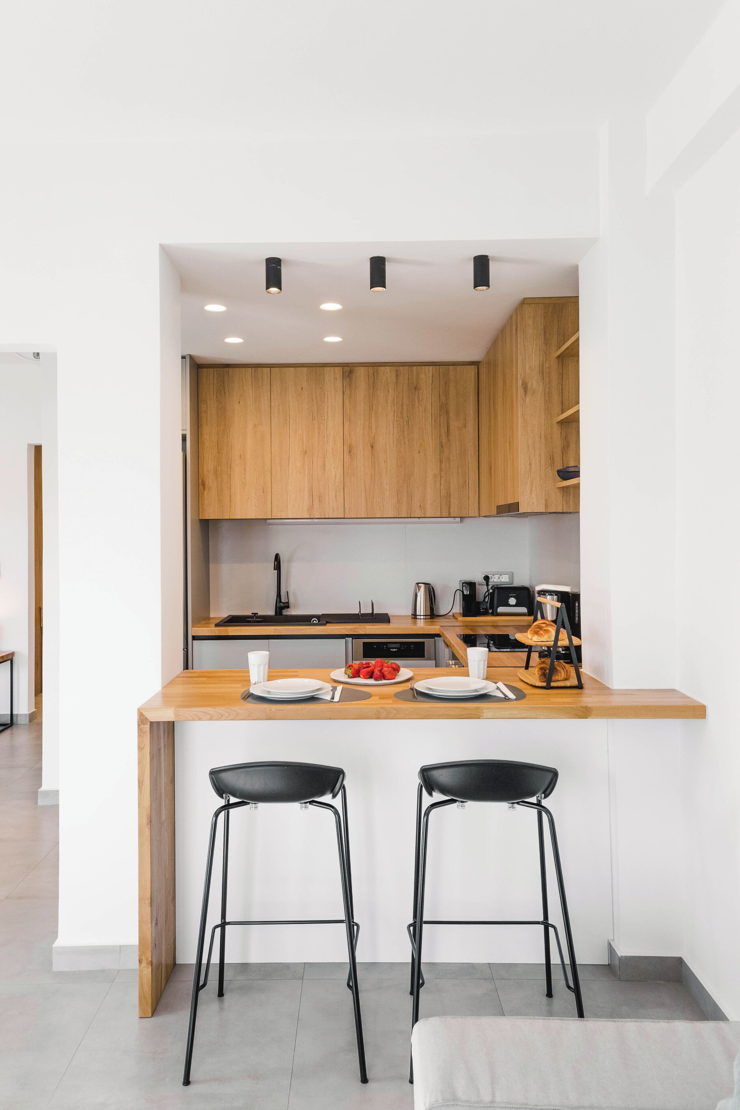 Una cucina moderna con mobili in legno, un'isola centrale con sgabelli e una macchina per il caffè.