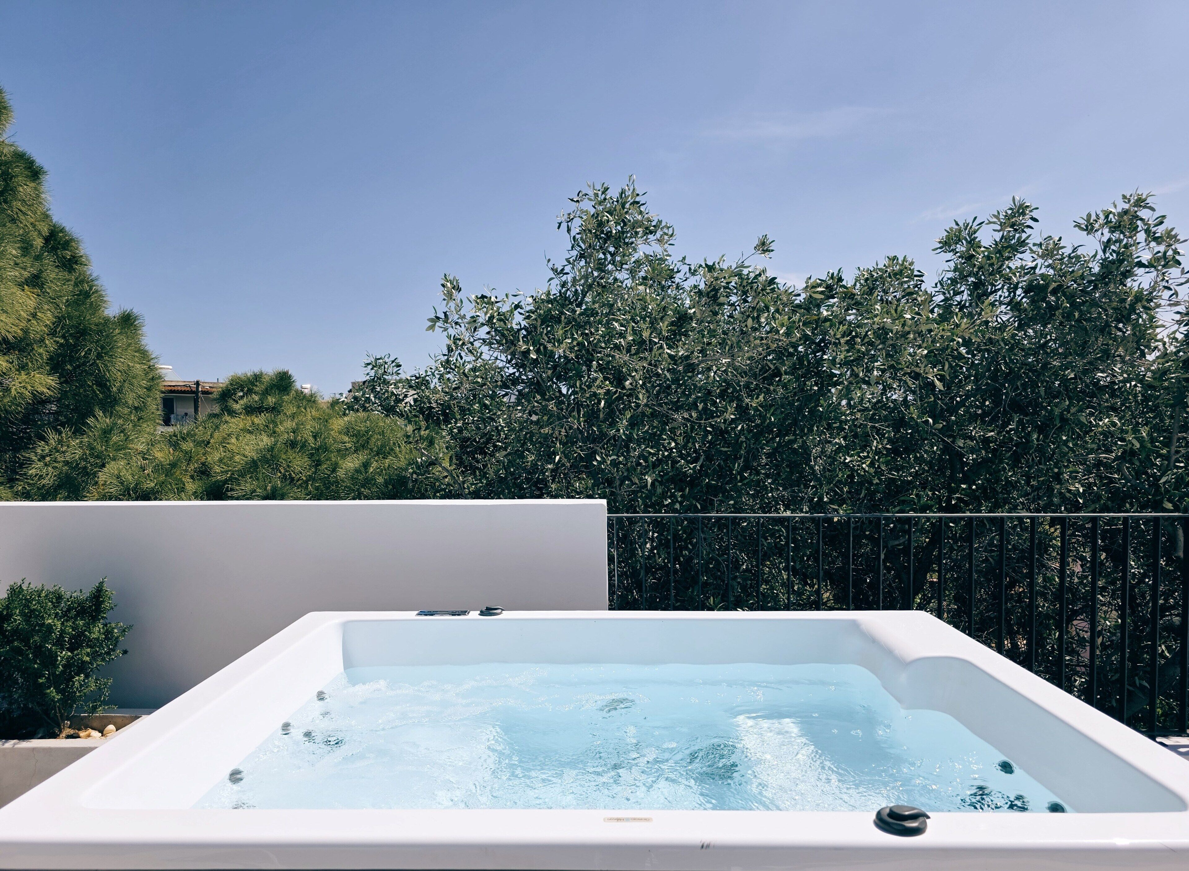 Un jacuzzi con vistas despejadas a los árboles circundantes y un edificio al fondo.