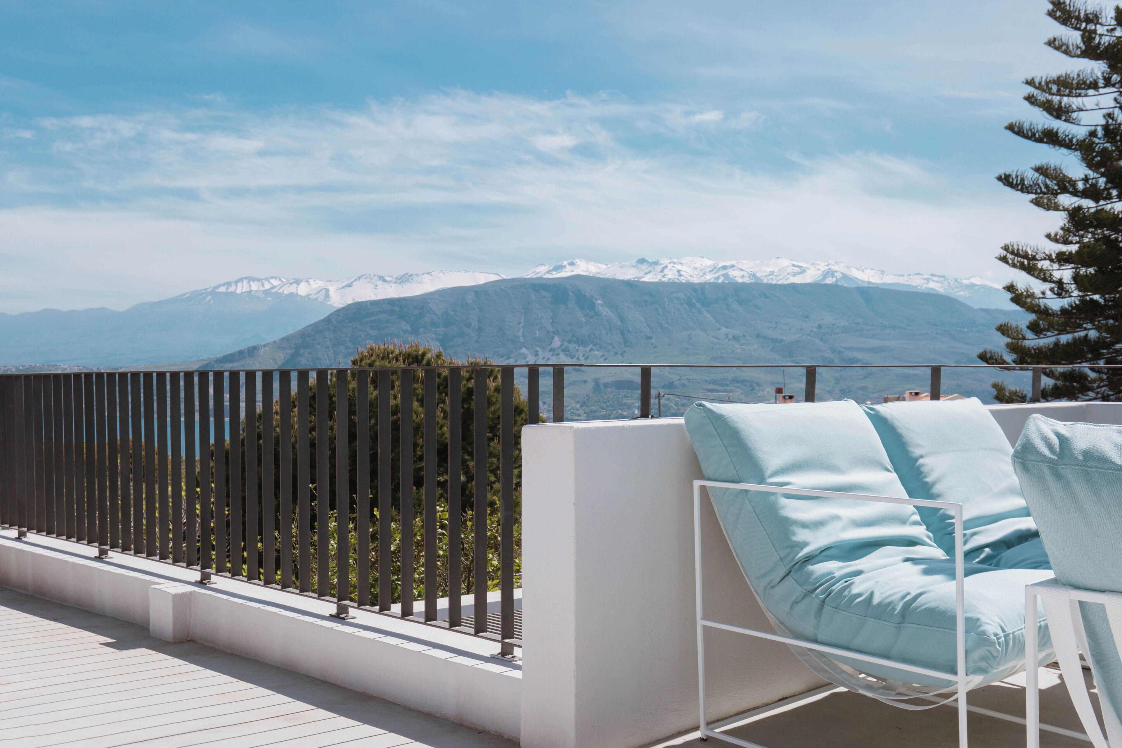 A balcony with a white chair and a view of snow-capped mountains.