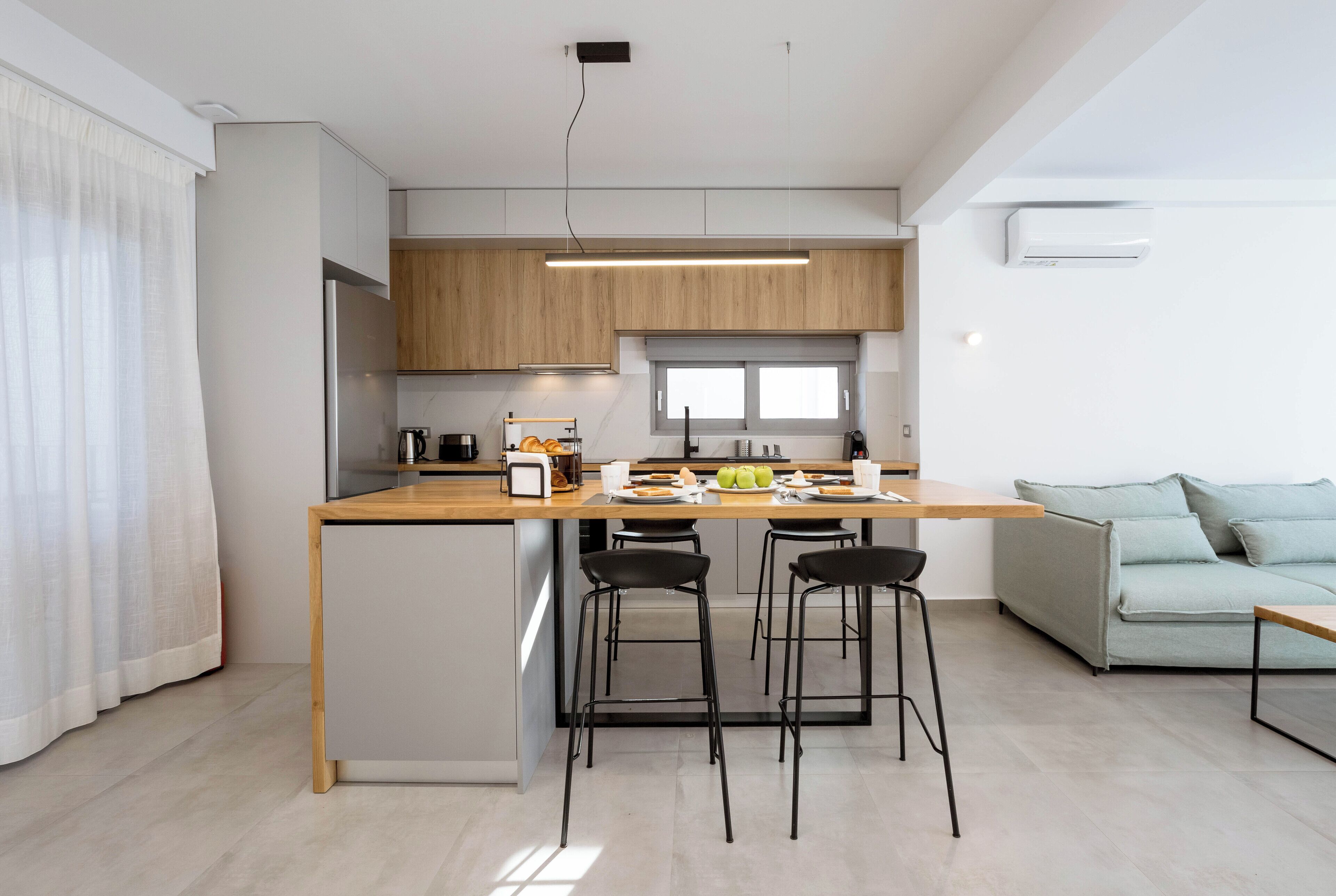 A modern kitchen with a wooden countertop, two bar stools, and a dining table.