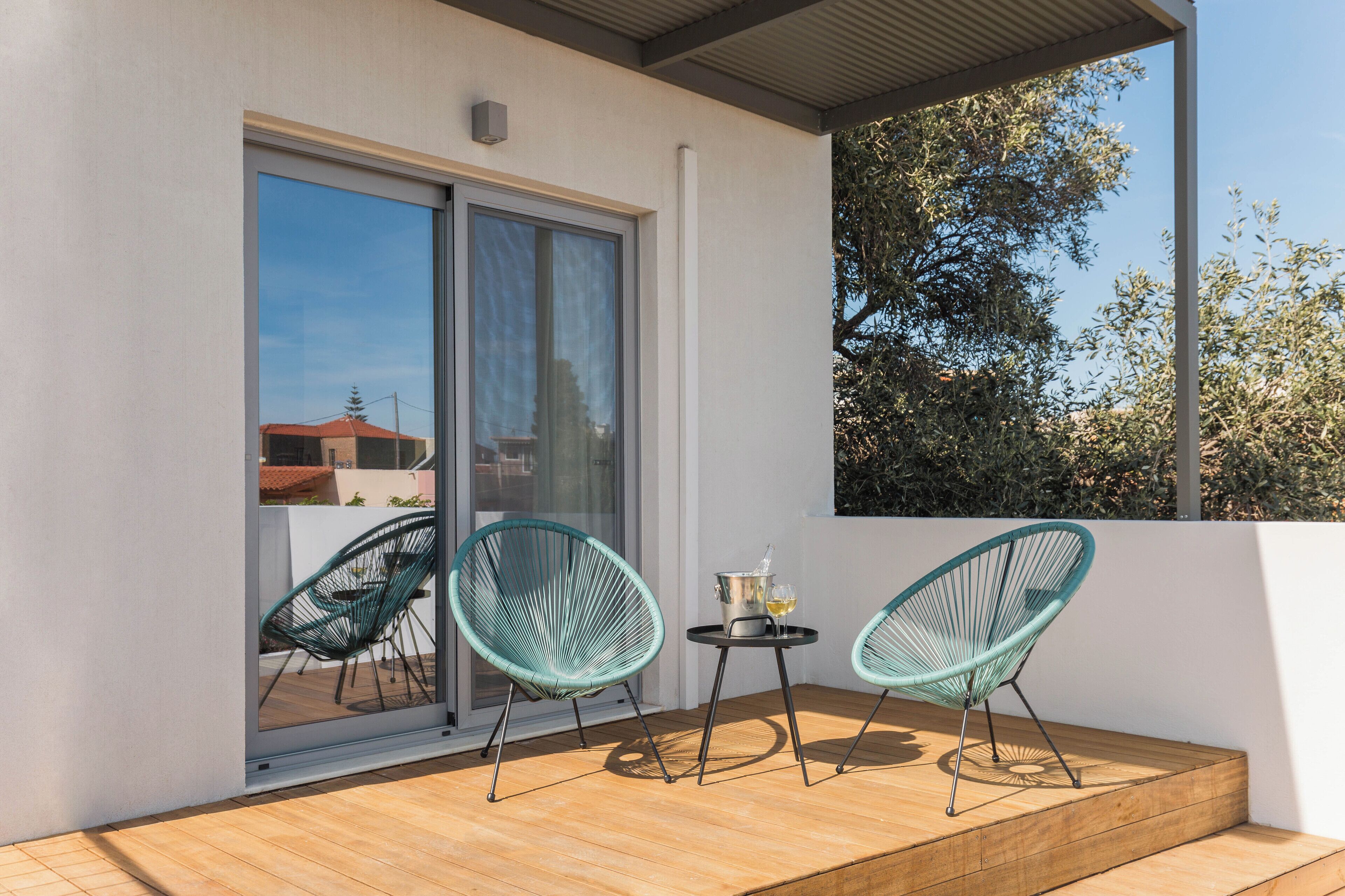 A balcony with two chairs and a small table with a drink.