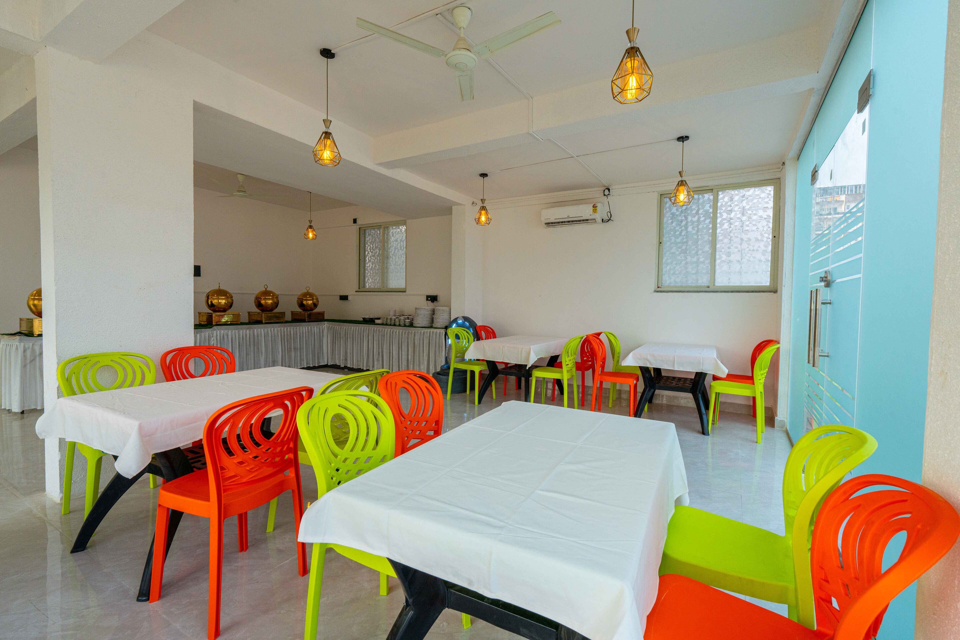 A dining area with multiple tables and chairs, ceiling fans, and hanging lights.