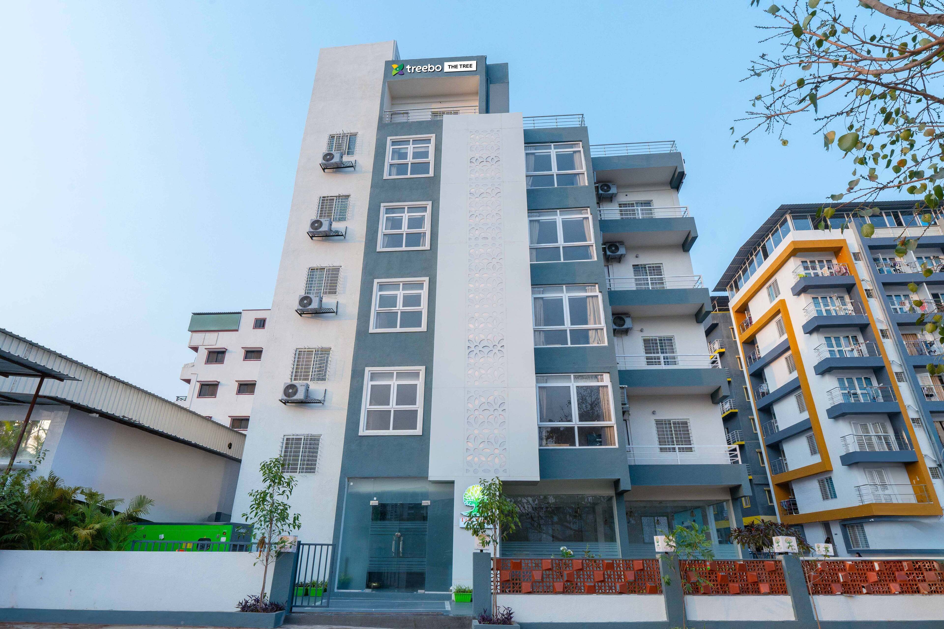 Un edificio de varios pisos con diseño moderno, que cuenta con balcones y una entrada central.
