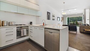 A modern kitchen with white cabinets, stainless steel appliances, and a dishwasher. - Luxury Interiors in Prime Location (Queenstown)