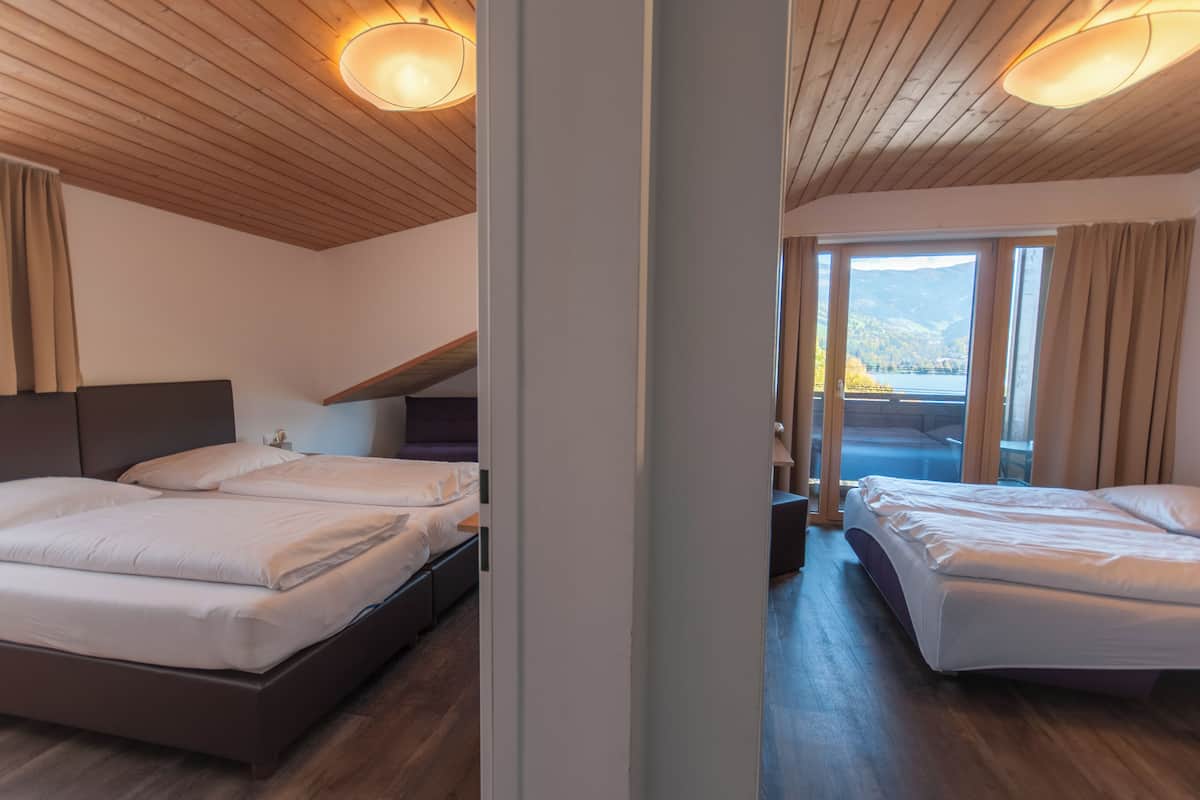 A hotel room with two beds, wooden ceiling, and a view of a lake.