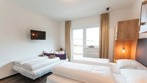 Een hotelkamer met twee bedden, een flatscreen televisie aan de muur, een raam met gordijnen en een houten hoofdeinde.