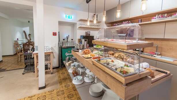 Een buffetruimte met diverse gerechten, een koffieapparaat en een zithoek met stoelen en een tafel.