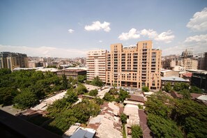 A high-rise building with multiple balconies, surrounded by trees and other buildings. - City View 2-bedroom Luxury Apartment on 13 Buzand Street by Sweet Home (Yerevan)