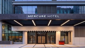 The exterior of the Mercure Hotel with a modern facade, large glass entrance, and a prominent name sign.