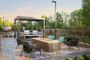 An outdoor patio with a stone floor, a grill, a fire pit, and wicker furniture. - TownePlace Suites by Marriott Pigeon Forge (Pigeon Forge)