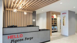 Un comptoir d’accueil avec une pancarte « BONJOUR, Pigeon Forge », des lambris en bois au plafond et une pancarte « PINCH » en arrière-plan.