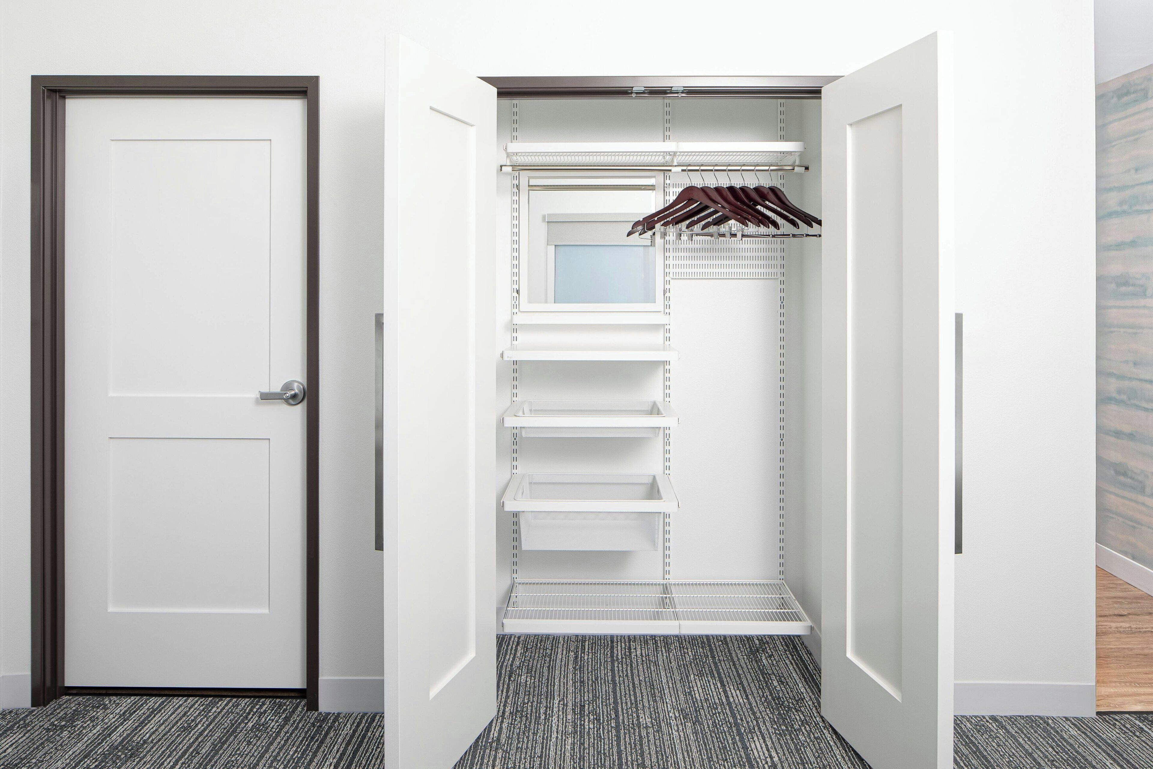 A walk-in closet with open doors, shelves, and a hanging rack.