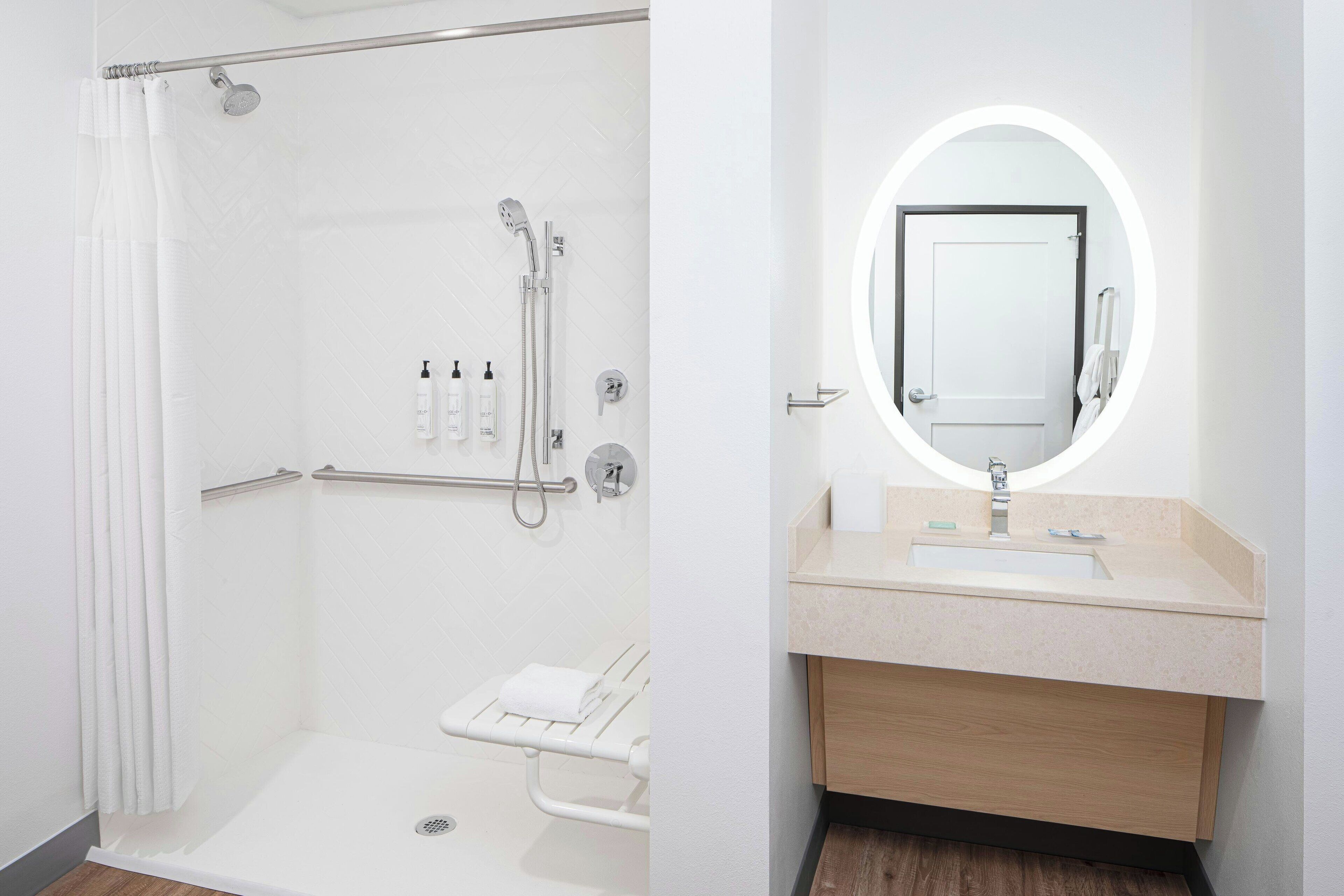Un baño moderno con ducha a ras de suelo, tocador con espejo y retrete.