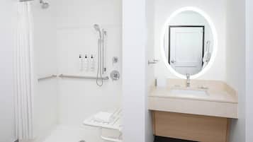 Un baño moderno con ducha a ras de suelo, tocador con espejo y retrete.