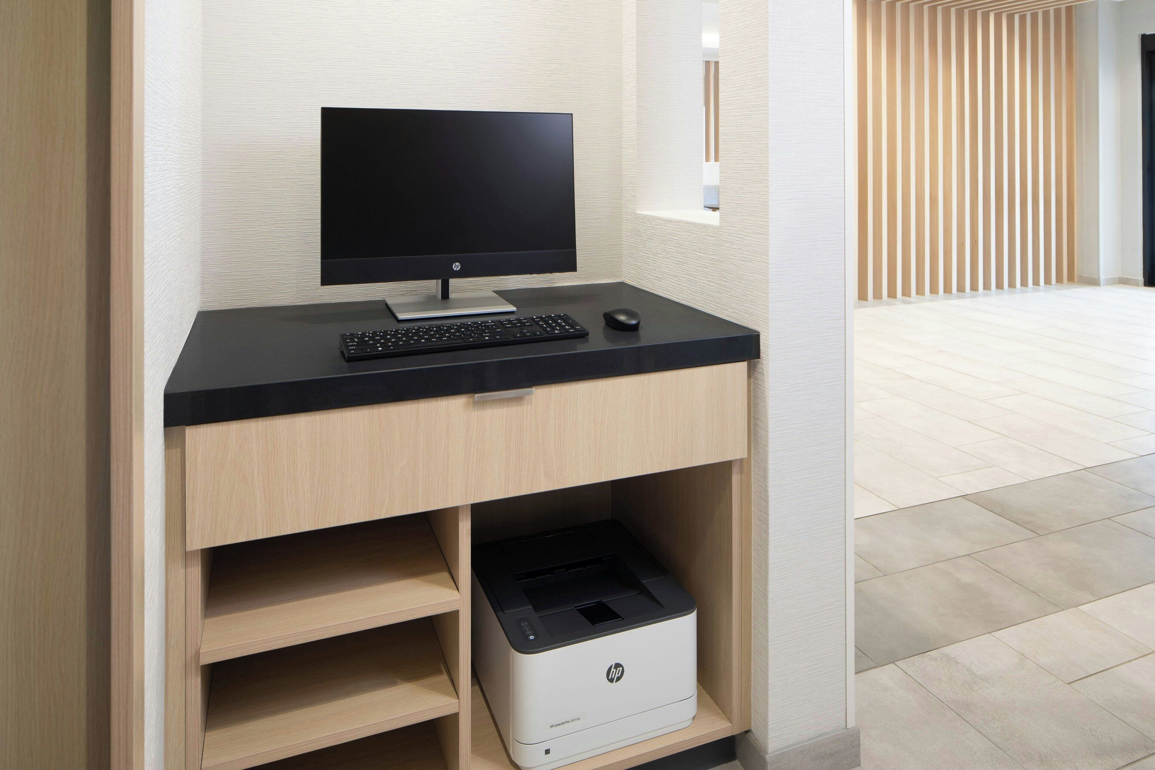 A modern office desk with a monitor, keyboard, and printer.