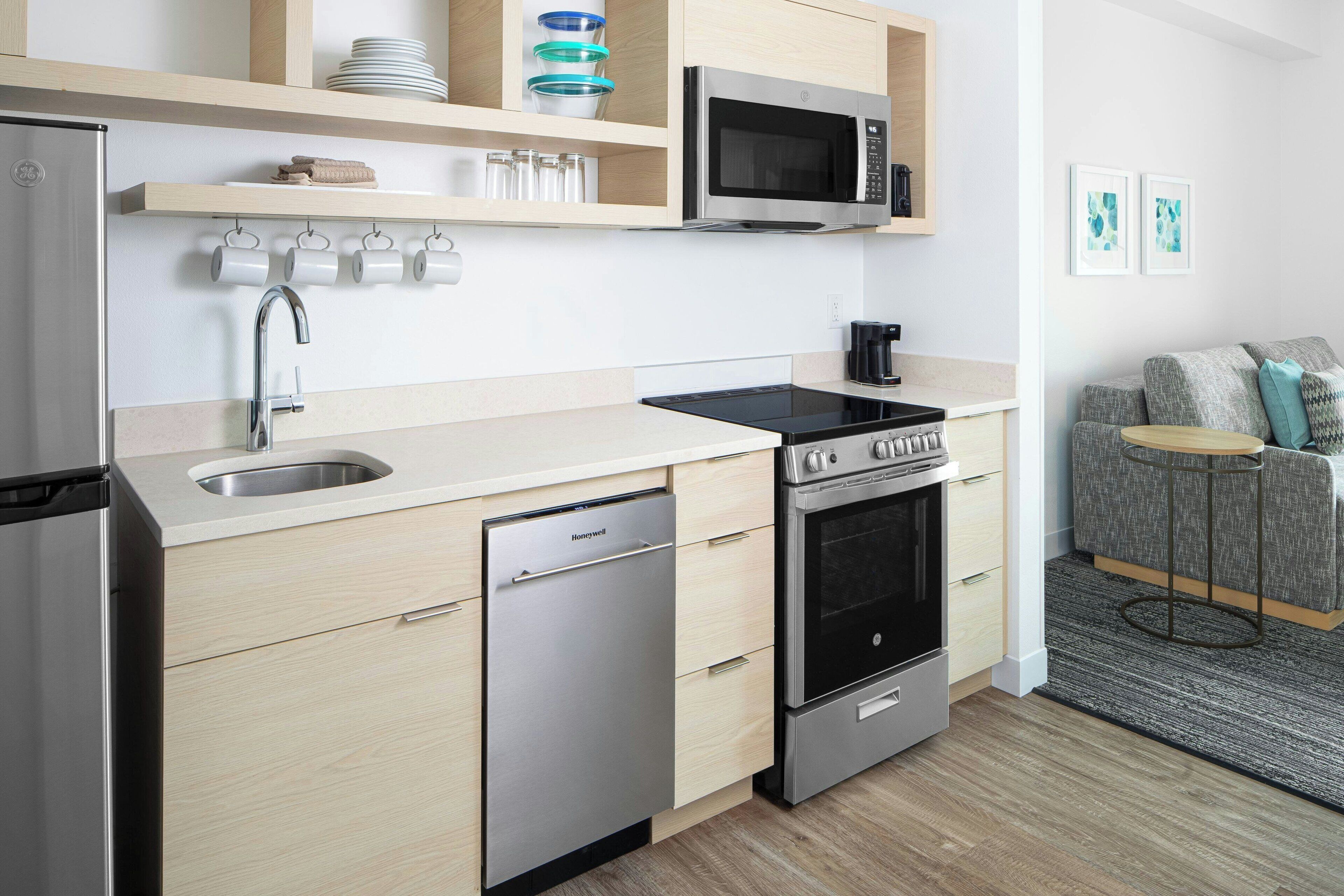 A modern kitchen with a dishwasher, stove, microwave, and a coffee maker.