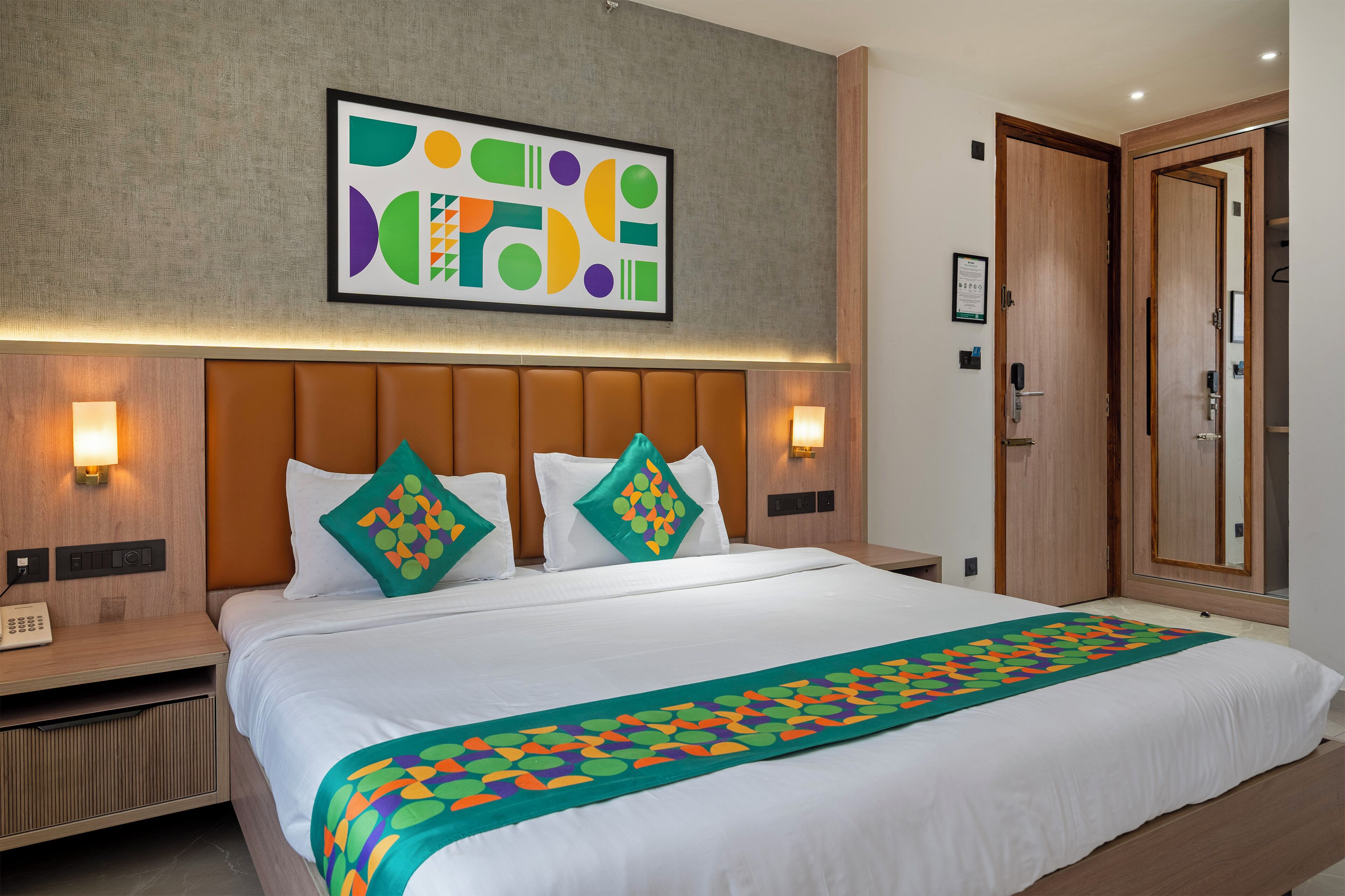 Ein Hotelzimmer mit einem großen Bett, zwei Nachttischen, einem Kopfteil und einem an der Wand befestigten Kunstwerk.