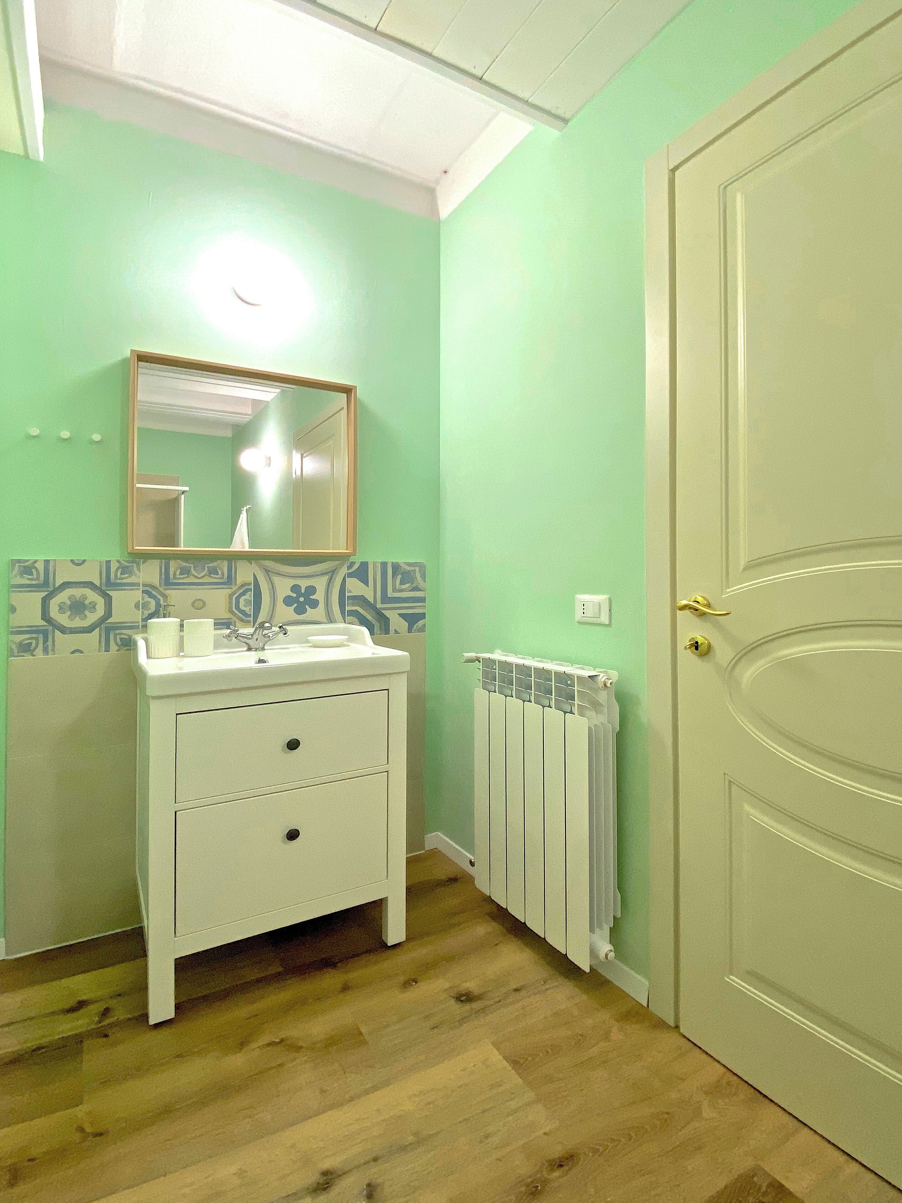 A bathroom with a white sink, mirror, and radiator.