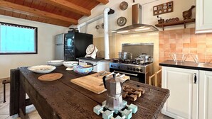 Eine Küche mit Holztisch, Herd, Kaffeemaschine und diversen Küchenutensilien.