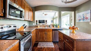 A modern kitchen with wooden cabinets, stainless steel appliances, and a granite countertop. - Waterfront Cabin | Near ARK | Large Family Retreat (Warsaw)