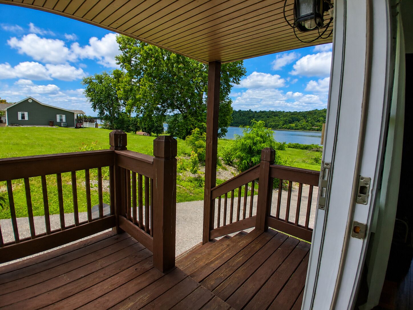 A wooden deck with a view of a lake and a house in the background.