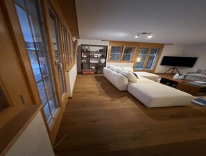 Un salon moderne avec un canapé, un téléviseur et un plancher en bois.
