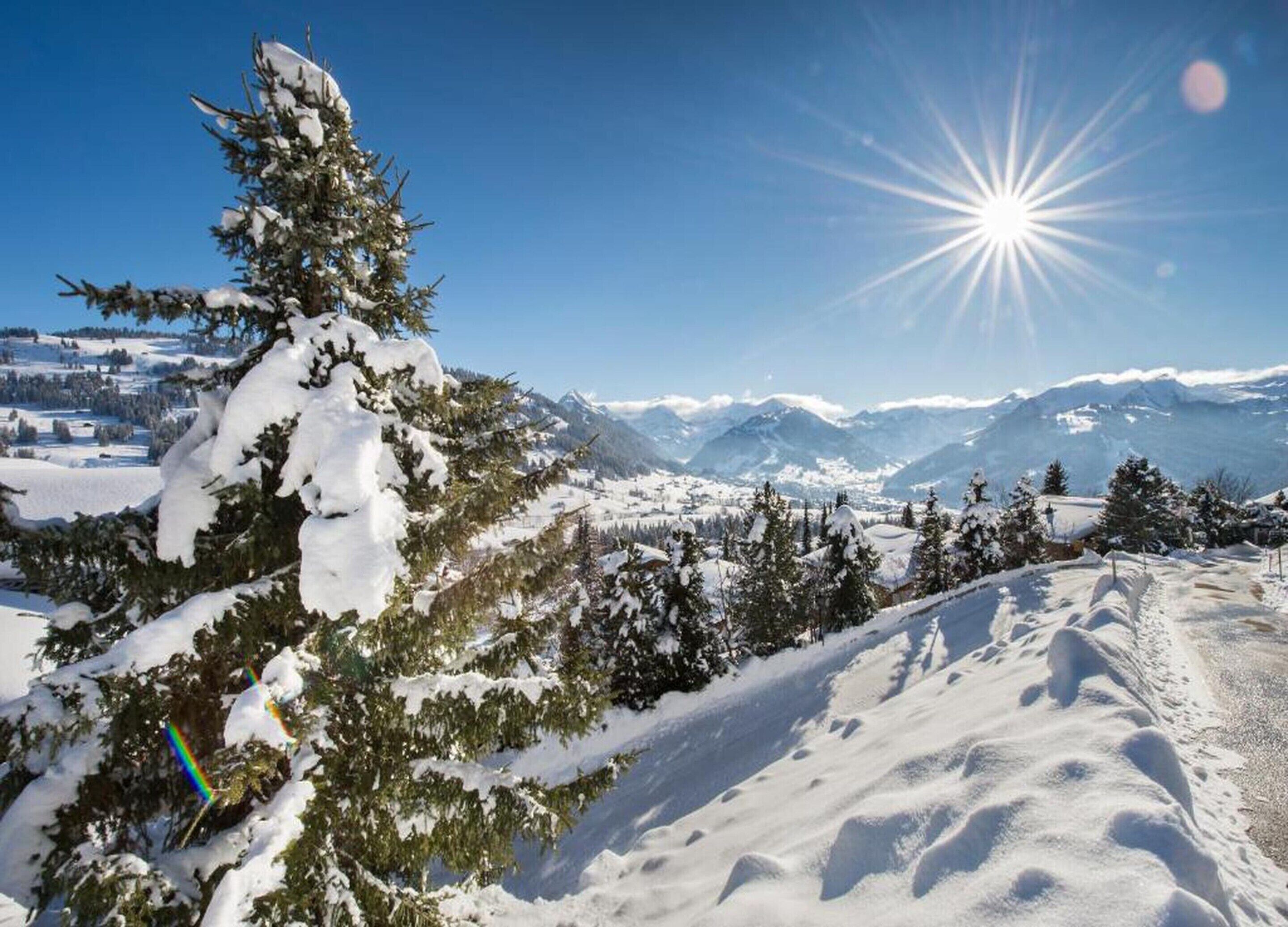 Een berglandschap bedekt met sneeuw, met een heldere lucht en een stralende zon.