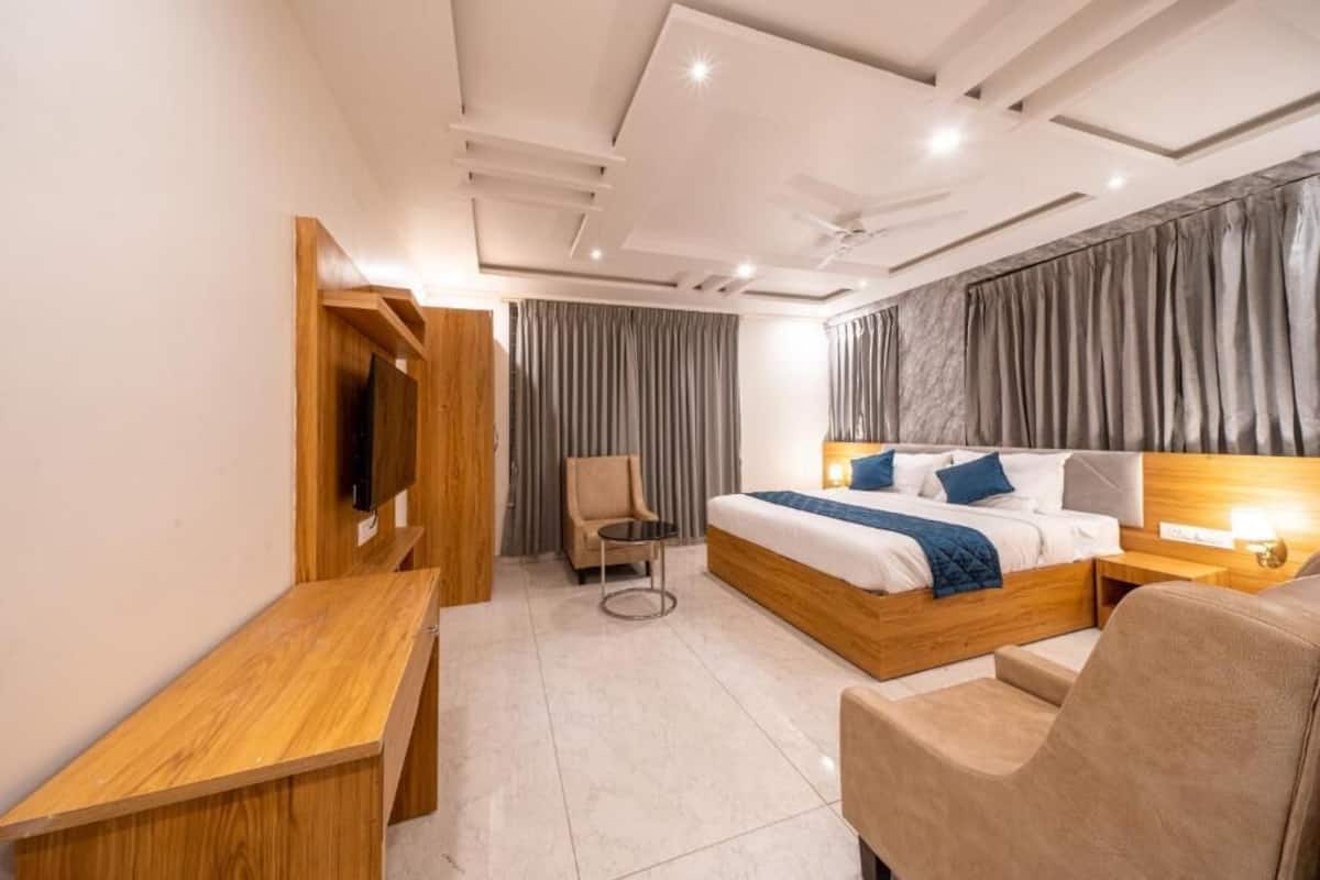 A modern hotel room with a wooden bed, a TV, a desk, and a chair.