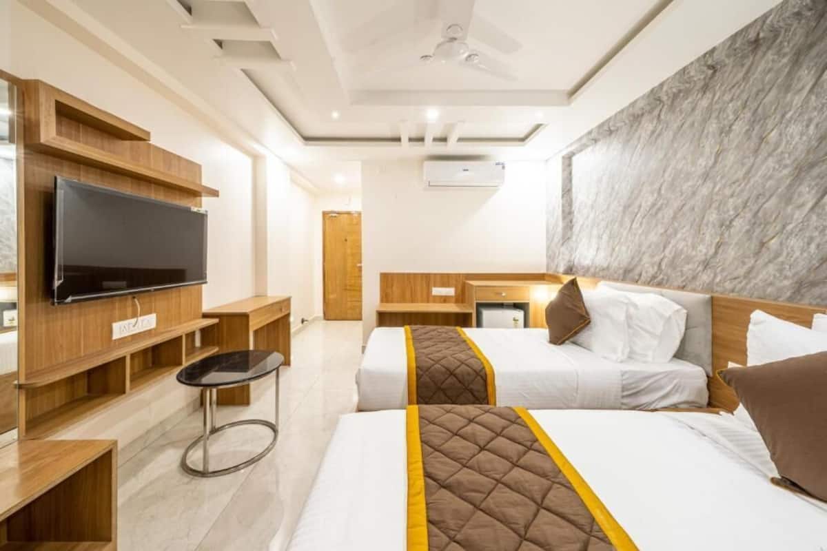 A hotel room with two beds, a TV, a desk, and a marble wall.