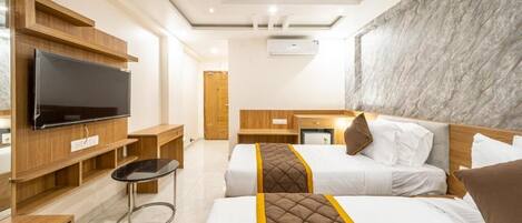 A hotel room with two beds, a TV, a desk, and a marble wall.