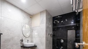 Egy modern fürőszoba, amelyben fehér WC-csésze, mosdókagyló és zuhanyzó található.
