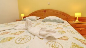 A neatly made bed with a compass-themed bedspread, two bedside lamps, and a wooden headboard.
