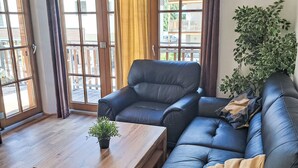 A modern living room with a black leather sofa, a wooden coffee table, and a potted plant. - Schönblick Mountain Resort & Spa by Interhome (Rauris)