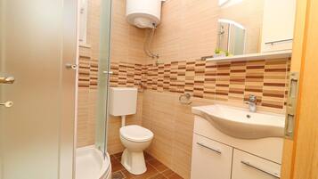 A bathroom with a toilet, sink, and shower.
