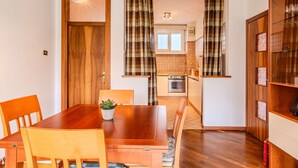 Un coin repas avec une table et des chaises en bois, une plante en pot et une cuisine en arrière-plan.