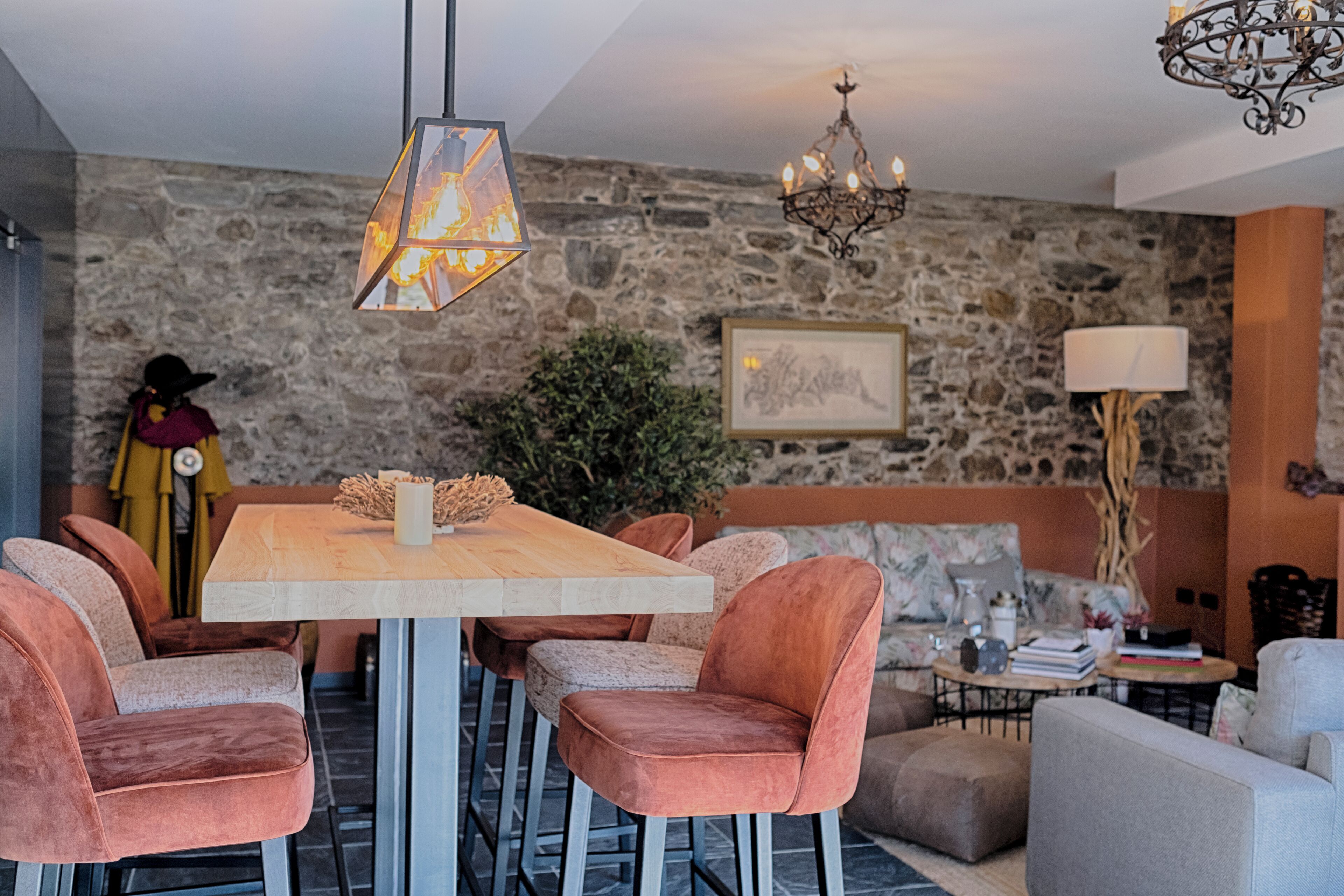 Un comedor con pared de piedra, una araña y una mesa con sillas.