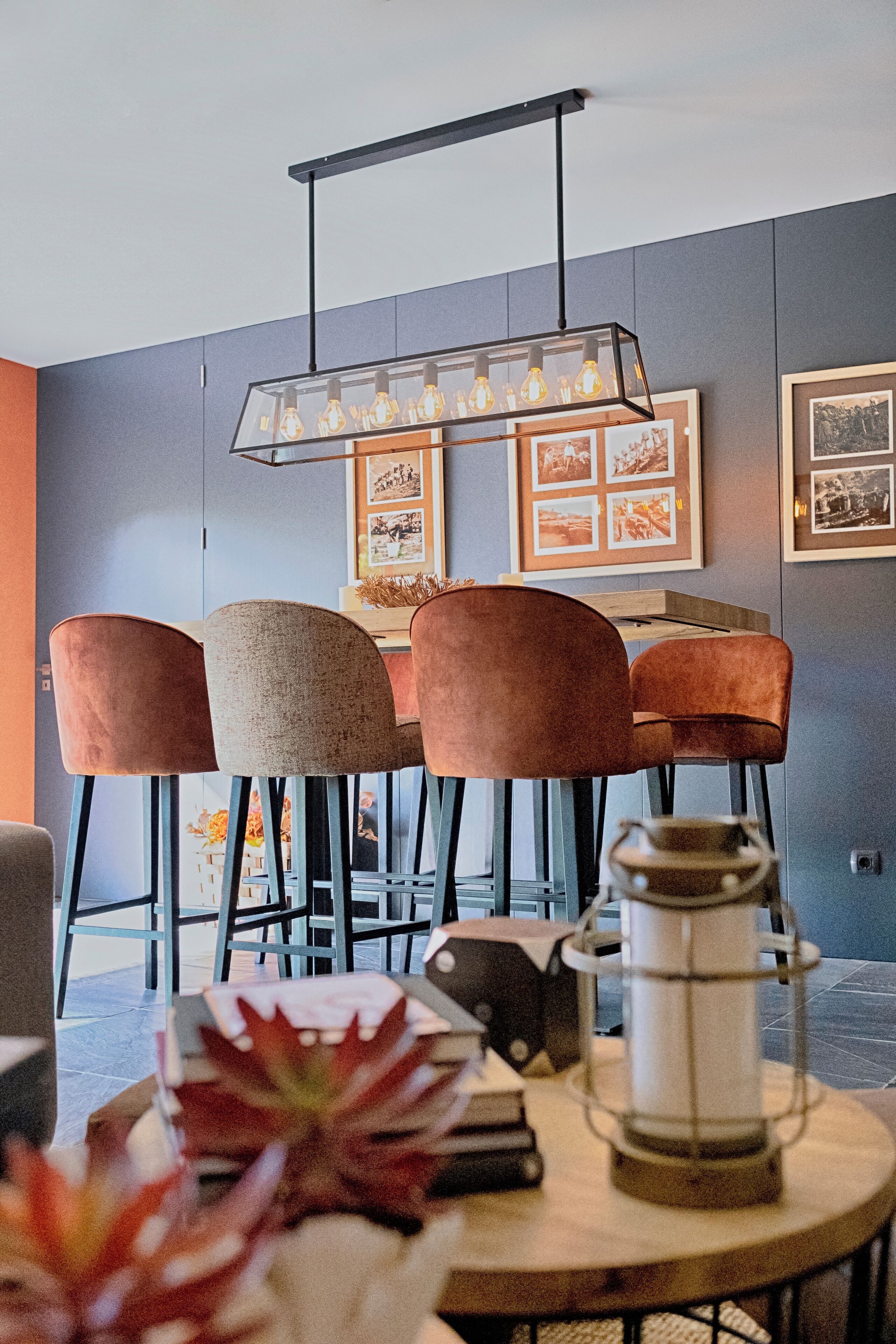 Un espace bar moderne, doté d’un luminaire original, de tableaux encadrés accrochés au mur et d’une table ronde surmontée d’une lanterne.