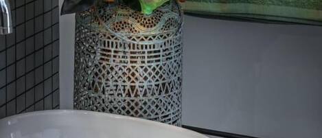 Un baño con un lavamanos blanco, un jarrón decorativo con flores y una pared verde con un letrero.