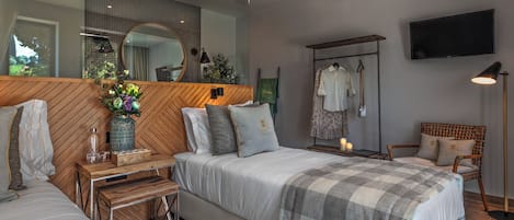 A modern bedroom with a large bed, bedside tables, a mirror, a TV, and a wardrobe.