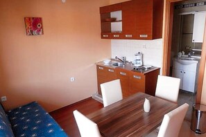 Cozy living space with a kitchenette, dining table, and sofa, perfect for travelers seeking a simple, functional stay.