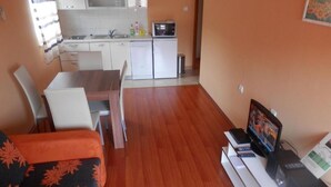 A compact living space with a dining area, kitchenette, and a TV setup. - Apartments St Rialto - Comfort One-Bedroom Apartment with Balcony and Sea View (Jelsa)